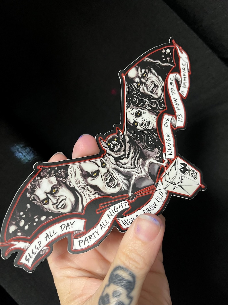 May include: A black and red bat-shaped sticker with vampire illustrations and the phrases "Sleep All Day", "Party All Night", and "Never Grow Old". The sticker also includes the text "It's Fun To Be A Vampire".
