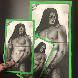 May include: Three black and white prints of a shirtless person with long dark hair, each with a green border. The person is depicted in a contemplative pose. The prints are arranged on a black surface.