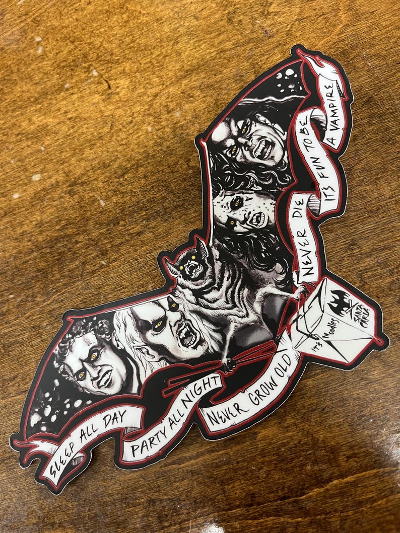 May include: A bat-shaped sticker with vampire imagery in black and white. The design includes the phrases "Sleep All Day", "Party All Night", and "Never Grow Old". The sticker also features the text "It's Fun to be a Vampire".