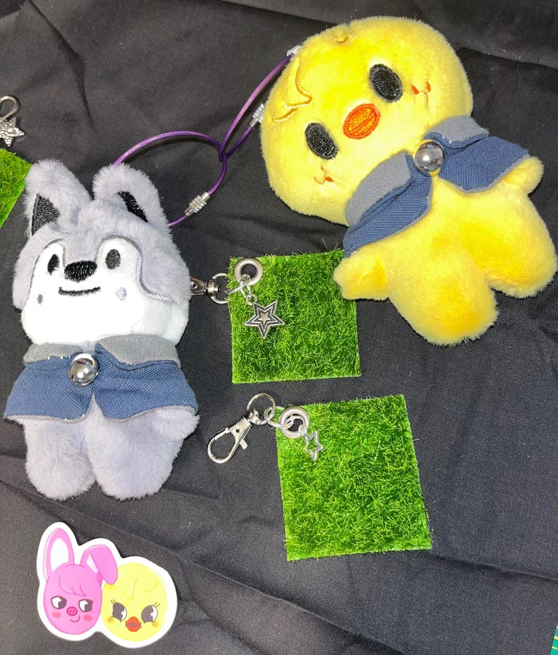 Puede incluir: Llaveros de peluche de un lobo y un pollito amarillo, ambos con trajes azules de estilo denim. Los llaveros est&aacute;n sujetos a parches cuadrados verdes con dijes de estrella. Tambi&eacute;n hay una pegatina de un conejito rosa y un pollito amarillo.