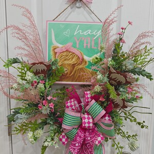 Corona de Vid de Verano: Bonitas vacas de las Highlands entre flores rosas y verdes, adornadas con un lazo de cinta rosa y verde. Y un cartel de "¡Hola a todos!".