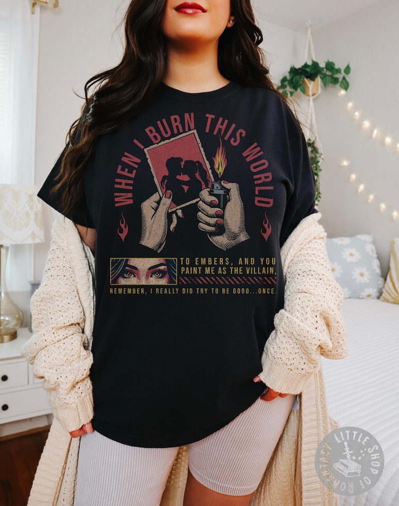 Pu&ograve; includere: T-shirt nero con la scritta "WHEN I BURN THIS WORLD" e una grafica di un accendino che accende una foto. La maglietta presenta anche il testo "TO EMBERS, AND YOU PAINT ME AS THE VILLAIN, REMEMBER, I REALLY DID TRY TO BE GOOD...ONCE."