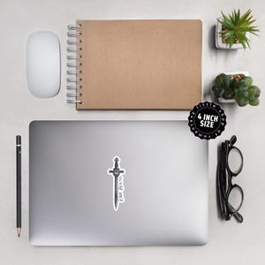 May include: A sticker featuring a black and white illustration of a sword with the text "Pure Found" in a gothic font. The sticker is 4 inches in size and is on a laptop.
