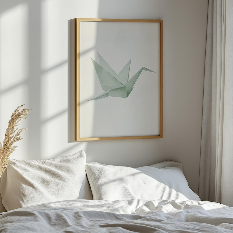 May include: A framed print of a green origami crane against a white background. The print is hanging on a white wall above a white bed with white bedding.