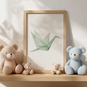 May include: Three teddy bears, one light brown, one light blue, and one tan, are sitting on a wooden shelf in front of a framed print of a green origami crane.
