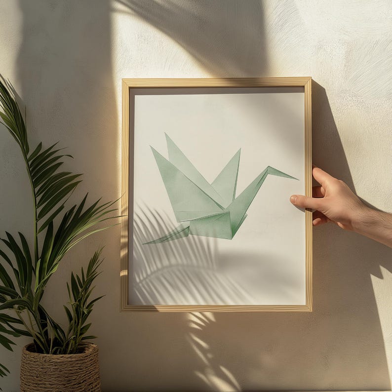 May include: A framed print of a green origami crane, a traditional Japanese paper folding art form. The crane is depicted in flight, with its wings spread wide. The print is set against a white background.