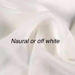 Op de afbeelding: Off-white stof met zachte plooien. De tekst "Natural or off white" is op de stof gedrukt. De stof lijkt glad en vloeiend te zijn, met subtiele kleurvariaties.
