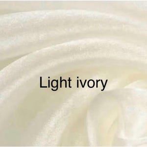 Op de afbeelding: Close-up van licht ivoorkleurige stof met zachte plooien. De tekst "Light ivory" staat in het zwart afgebeeld. De stof heeft een gladde textuur en een subtiele glans.
