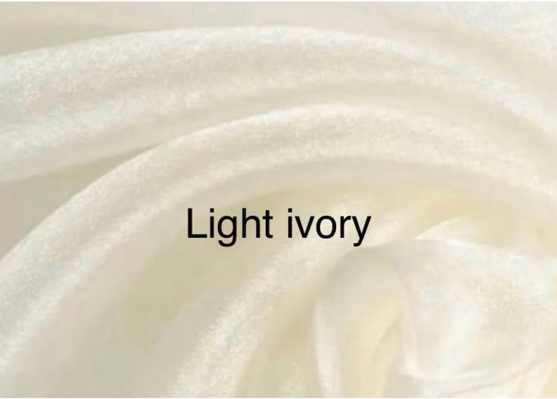 Op de afbeelding: Close-up van licht ivoorkleurige stof met zachte plooien. De tekst "Light ivory" staat in het zwart afgebeeld. De stof heeft een gladde textuur en een subtiele glans.
