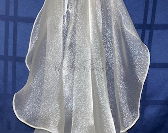 May include: A white, shimmering bridal veil with a rounded edge. The veil is made of a sheer, sparkly fabric and is gathered at the top. The background is a dark blue fabric.