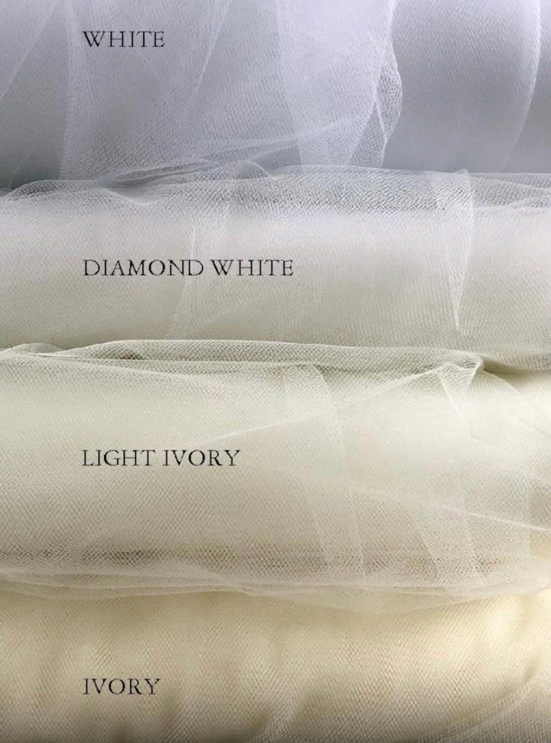 Puede incluir: Primer plano de cuatro tonos diferentes de tela de tul: blanco, blanco diamante, marfil claro e marfil. Los nombres de los colores est&aacute;n impresos encima de cada muestra. El tul tiene un tejido fino y abierto.