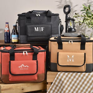 May include: Three insulated cooler bags in black, orange, and tan, each with a front pocket and top handle. The black bag has the initials "MF", the orange bag has "MILTON" and a mountain graphic, and the tan bag has the initials "M IVI".