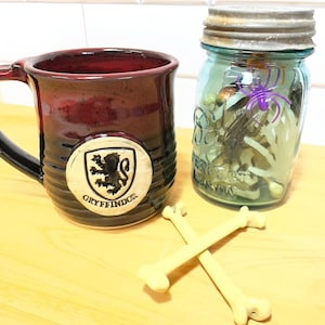 May include: A set of three ceramic mugs with a speckled, matte finish. The mugs are in shades of cream, light gray, and dark gray. Each mug has a simple, minimalist design, perfect for coffee or tea.