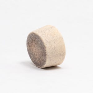 May include: A small, round, white ceramic bowl with a speckled brown glaze. The bowl is slightly tilted to the side.