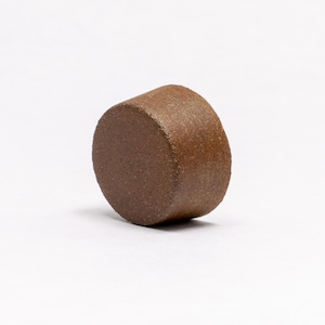 May include: A brown ceramic bottle stopper with a textured surface.