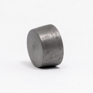 Op de afbeelding: Een grijze metalen dop met een glad, licht getextureerd oppervlak. De dop is rond en heeft een licht afgeronde bovenkant.