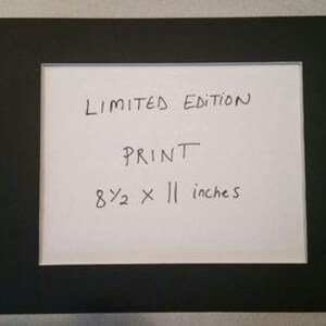 Puede incluir: Una moldura negra con un inserto de papel blanco. El inserto de papel tiene el texto "LIMITED EDITION PRINT 8 1/2 x 11 inches" escrito en tinta negra.