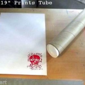 Puede incluir: Una impresi&oacute;n blanca de 13" por 19" est&aacute; enrollada en un tubo de env&iacute;o marr&oacute;n. La impresi&oacute;n tiene un sello de calavera rojo.