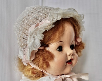 Gorrito de bebé antiguo de encaje de red: cinta rosa y rosetas, estilo eduardiano.