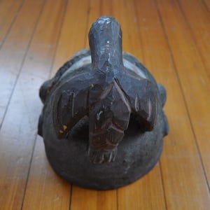 Puede incluir: Una escultura de madera tallada a mano, de color marr&oacute;n oscuro, que representa una tortuga. La tortuga tiene una superficie texturizada y rugosa, con una cabeza y aletas talladas con detalle. La escultura est&aacute; sobre un suelo de madera.