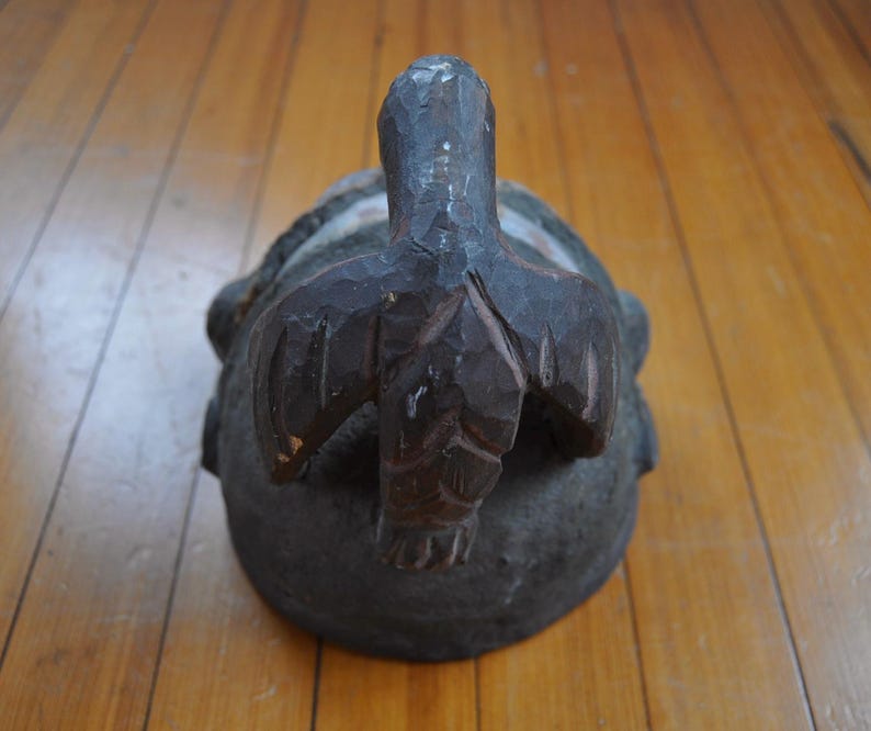 Puede incluir: Una escultura de madera tallada a mano, de color marr&oacute;n oscuro, que representa una tortuga. La tortuga tiene una superficie texturizada y rugosa, con una cabeza y aletas talladas con detalle. La escultura est&aacute; sobre un suelo de madera.
