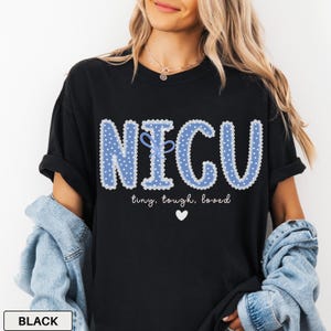 May include: Black t-shirt with the text "NICU" in blue polka dot letters with a bow. Below the text are the words "tiny, tough, loved" and a white heart. The shirt is a casual style.