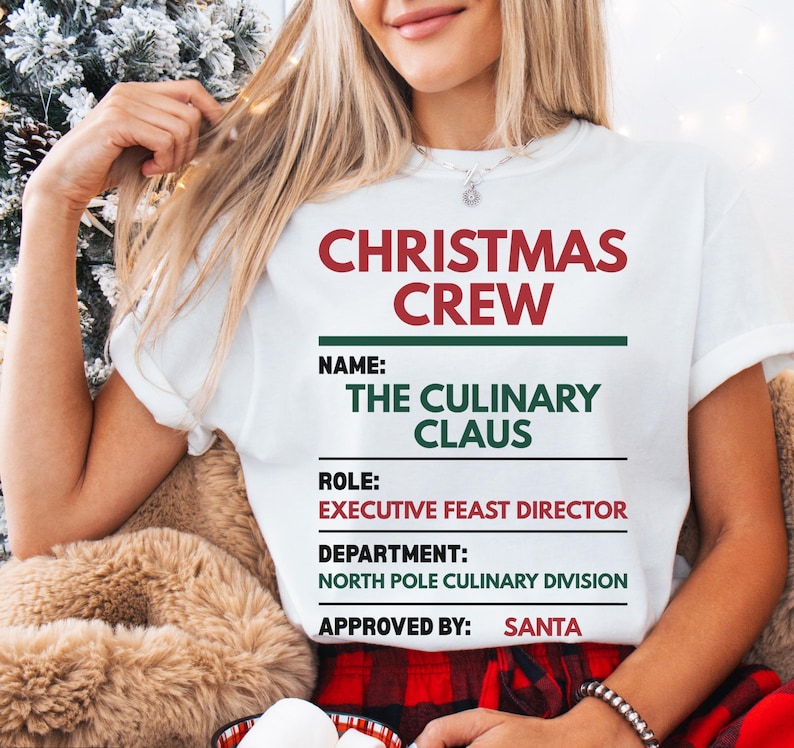 May include: A white short-sleeved t-shirt featuring the red and green text CHRISTMAS CREW, NAME: THE CULINARY CLAUS, ROLE: EXECUTIVE FEAST DIRECTOR, DEPARTMENT: NORTH POLE CULINARY DIVISION, and APPROVED BY: SANTA, arranged in a structured list format.