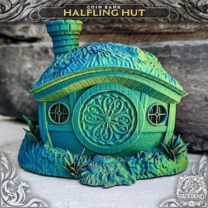 May include: A green and blue 3D printed coin bank shaped like a halfling hut with a round door and a chimney. The hut is surrounded by green grass and flowers.