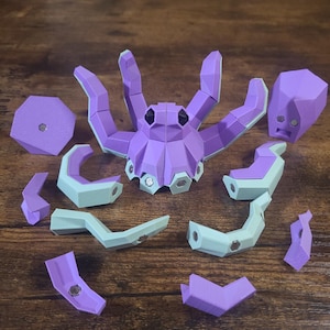 Könnte beinhalten: Ein 3D-Puzzle aus lila und grün, das eine Krake mit acht Tentakeln darstellt. Das Puzzle ist zerlegt und auf einer Holzoberfläche ausgelegt.