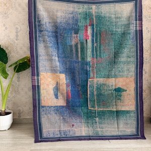 Könnte beinhalten: Eine rechteckige Tagesdecke mit Patchwork-Design in den Farben Dunkelblau, Petrol und gedämpftem Pfirsich. Der Stoff weist durchgehend sichtbare Steppnähte auf und ist von einem dunkelvioletten Rand mit feinen Streifenakzenten eingefasst.