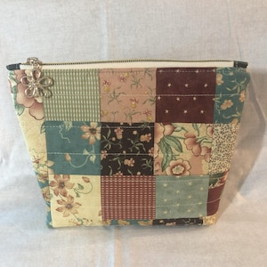 Quilted and lined zipper bag with an adorable flower zip pull.  Bag has a patchwork front and column style back.