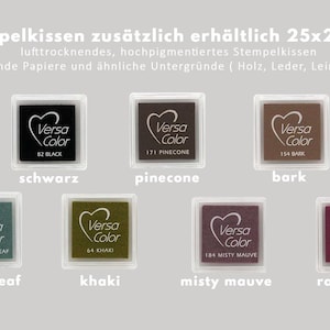 Peut inclure: Huit tampons encreurs de diff&eacute;rentes couleurs, dont noir, marron, vert et rouge. Chaque tampon est &eacute;tiquet&eacute; avec le nom de la marque "Versa Color" et un nom de couleur, comme "Noir", "Pinecone" et "Bark". Les tampons encreurs sont dispos&eacute;s en deux rang&eacute;es de quatre, avec le texte "Stempelkissen zus&auml;tzlich erh&auml;ltlich 25x25mm" en haut.