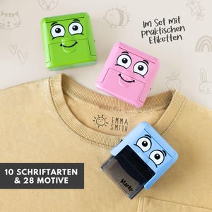 Könnte beinhalten: Drei farbenfrohe Stempel mit Cartoon-Gesichtern in Grün, Rosa und Blau werden auf einem gelben T-Shirt gezeigt. Die Stempel haben ein lächelndes Gesichtsdesign. Das T-Shirt hat den Text "Emma Smith" und eine Sonnengrafik. Der Text "10 Schriftarten & 28 Motive" ist ebenfalls enthalten.