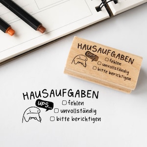 Könnte beinhalten: Ein Holz-Stempel mit einer Comicfigur und dem Text "Hausaufgaben" und "Ups..." mit Kontrollkästchen für "fehlen", "unvollständig" und "bitte berichtigen".