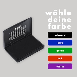 May include: A black ink pad with the text "trodat" on the lid. The ink pad is open and the ink pad is visible. The text "w&auml;hle deine farbe" is displayed above five color options: black, blue, green, red, and violet.