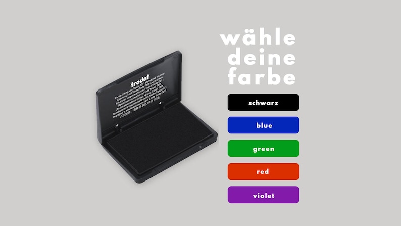 May include: A black ink pad with the text "trodat" on the lid. The ink pad is open and the ink pad is visible. The text "w&auml;hle deine farbe" is displayed above five color options: black, blue, green, red, and violet.