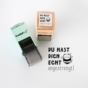 May include: Two stamps, one mint green and one tan, with the text "DU HAST DICH ECHT angestrengt!" and a cartoon bee. The mint green stamp has the brand name "trodat edy" printed on it.