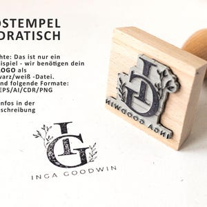 May include: A wooden square stamp with a black and white design of the letters "IG" with floral accents. The text "INGA GOODWIN" is printed on the stamp. The stamp is on a white surface.