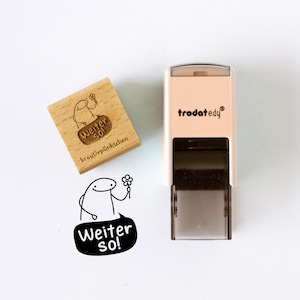 May include: A wooden stamp and a self-inking stamp featuring the text "Weiter So!" and a cartoon character with a flower. The wooden stamp has the text "kreativpünktchen" and the self-inking stamp has the brand name "trodatedy".