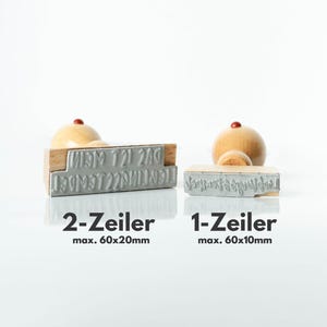 May include: Two wooden stamps with metal lettering, one larger and one smaller, with wooden handles. The larger stamp is labeled "2-Zeiler" and the smaller one is labeled "1-Zeiler". The text "max. 60x20mm" and "max. 60x10mm" is also visible.