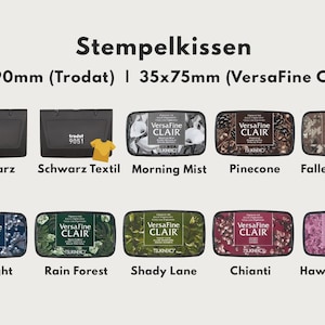 May include: An image showcasing various stamp pads, including black Trodat 9051 models and VersaFine Clair pads in multiple colors and designs. The pads are labeled with names like "Morning Mist," "Pinecone," and "Twilight."