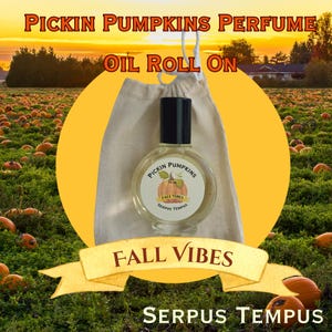 May include: A clear glass perfume bottle with a black cap and a label that reads "Pickin Pumpkins". The bottle is in a beige drawstring bag. The words "Fall Vibes" and "Serpus Tempus" are also visible. The background shows a pumpkin patch.