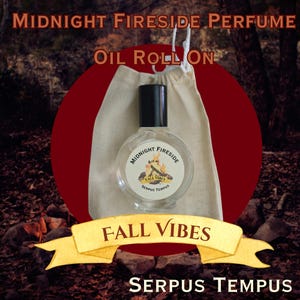 May include: A clear glass perfume bottle with a black cap, labeled "Midnight Fireside" and "Fall Vibes." The bottle is inside a beige drawstring bag, set against a dark red circle and a background of a forest. Text includes "Oil Roll On" and "Serpus Tempus."
