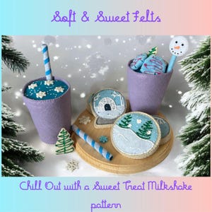 Puede incluir: Una escena artesanal de fieltro con una taza de batido morada con una pajita a rayas azules y blancas, y una taza llena de golosinas de fieltro azul. La escena incluye galletas de fieltro con diseños de invierno, un árbol de Navidad de fieltro y el texto "Soft & Sweet Felts" y "Chill Out with a Sweet Treat Milkshake pattern."