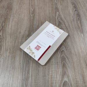 May include: A brown notebook with a red spine and a white label that says "Writing Comfort Soft Cover Journal Refill 90 GSM Acid Free Paper Designed for Ink & Gel Pens 100 Sheets". The label also has a floral design and a QR code.