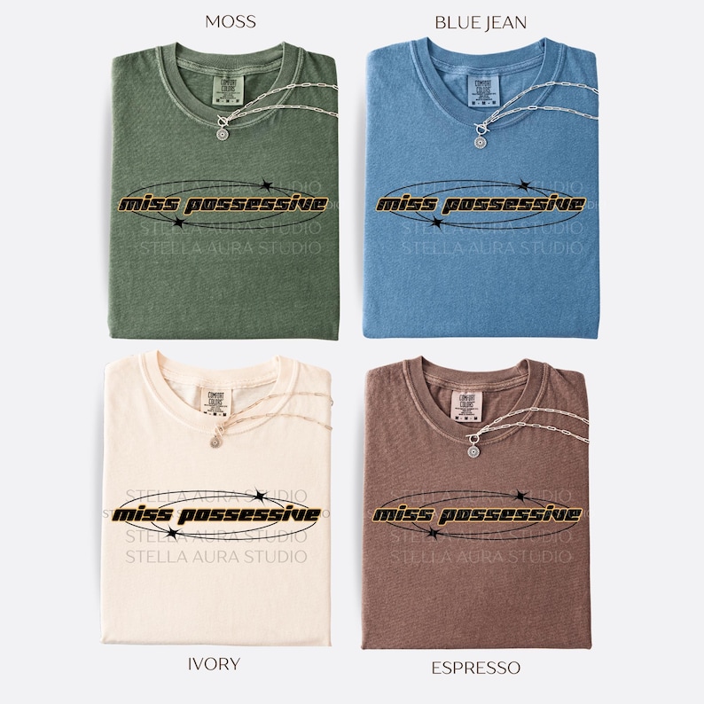 May include: Four t-shirts in different colors: moss green, blue jean, ivory, and espresso. Each t-shirt has the text 'miss possessive' printed in black with a gold outline and a circle of stars around it.