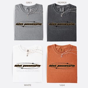 May include: Four t-shirts in different colors: grey, dark grey, white, and orange. Each t-shirt has the text 'miss possessive' printed on the front in black with a yellow outline and a circle around the text with black stars.