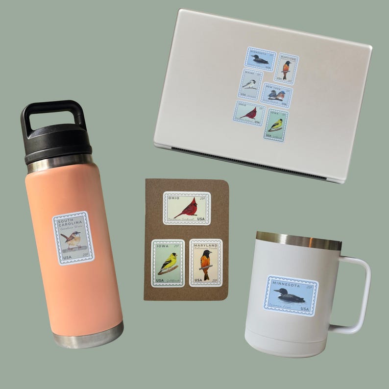 May include: An assortment of items featuring bird-themed stickers. A peach-colored water bottle, a white mug, and a laptop are adorned with stickers resembling vintage postage stamps. A small notebook displays similar stamps. The stickers showcase various bird illustrations.