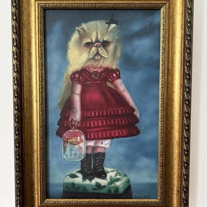 Puede incluir: Pintura enmarcada que representa un gato con cuerpo de niño, vestido con un vestido rojo y botas negras. El gato sostiene un terrario de cristal con un objeto dorado en su interior. La pintura tiene un marco dorado ornamentado.