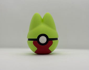 May include: A green and red novelty item with a black band and white circle. The item has a rounded shape with two pointed ears on top. The bottom portion is red, and the top is green.